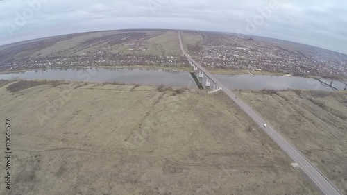 Flying over the town by the side of the river and bridge with cars driving over it. Belaya Kalitva, Russia photo