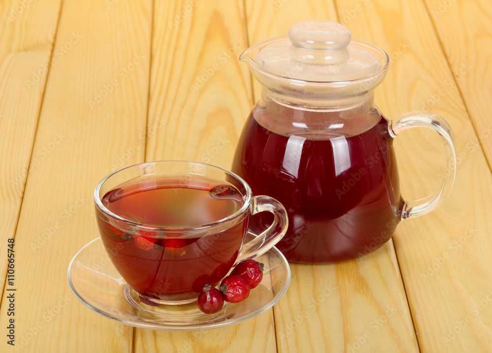 Jug and cup of rosehip drink on the background light wood. Jug and cup of rosehip drink on the background light wood.