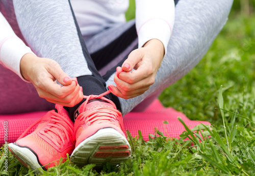 Woman tying sneakers on grass