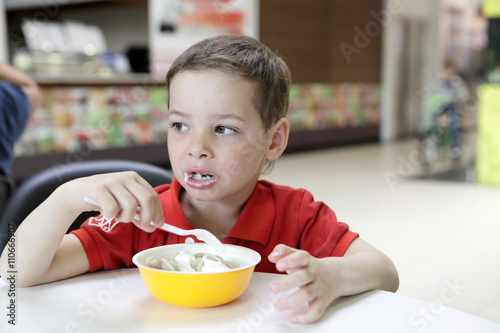 Kid eating meat dumplings with sour cream
