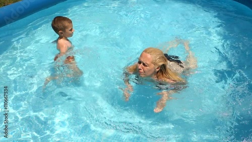 Mother learning her son to swim in the pool 