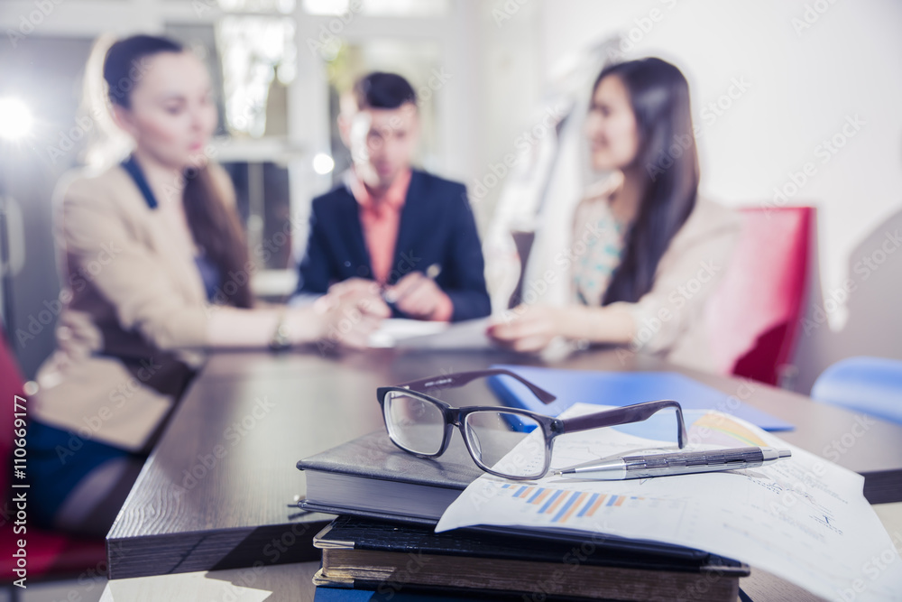 Obraz premium financial chart near dollars seen by unfocused glasses ( colleagues meeting to discuss their future financial plans only silhouettes being viewed )