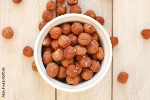 Hazelnuts in the bowl on the wooden background