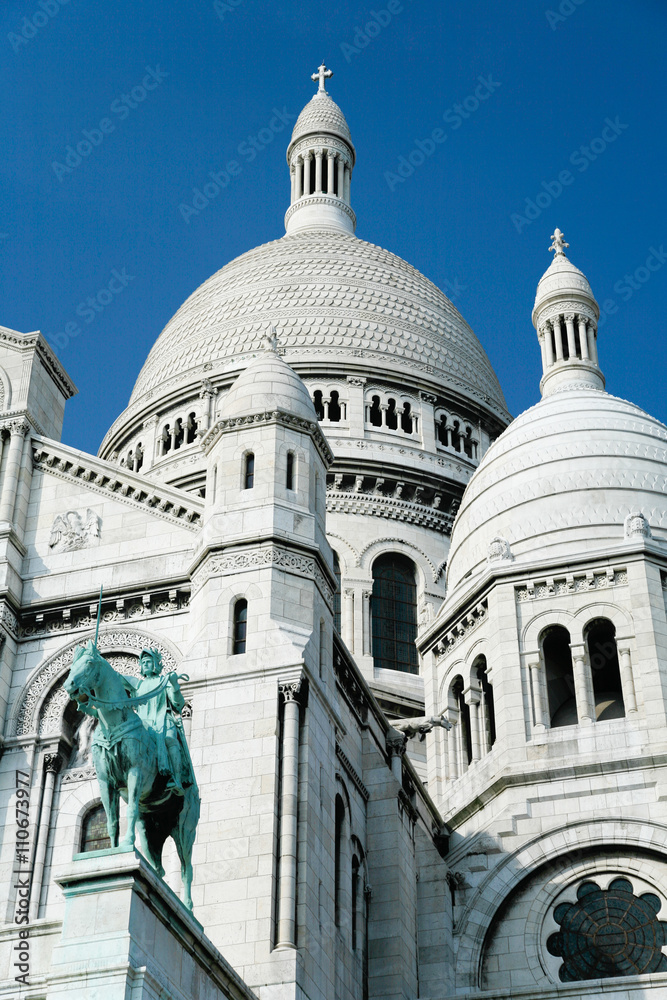 the catholic church Basilica of Sacre Coeur, or Sacred Heart, with dome and statue of Saint Joan of Arc, public monument landmark from year 1914 in Montmartre, Paris, France, Europe