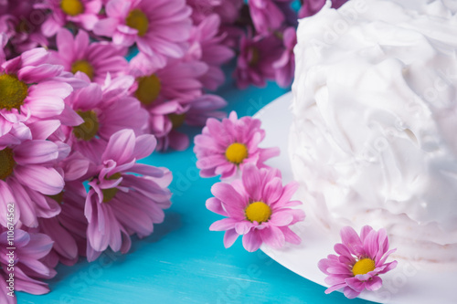White creamy cake with flowers on the blue wooden background. Shallow depth of field.