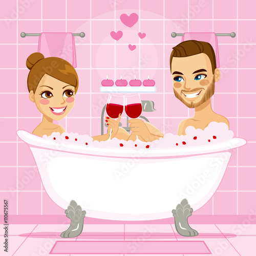 Attractive couple in love enjoying a relaxing pink bubble bath making a toast with red wine in bathtub