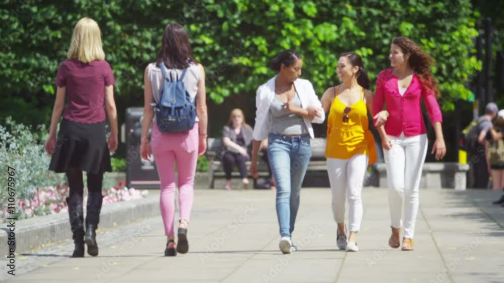 Happy attractive female friends chatting as they walk through city Happy attractive female friends chatting as they walk through city