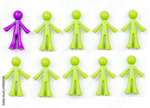 Ten pieces of generic, human shaped plastic pieces in green and purple. One piece is purple, nine pieces are green. Could indicate a demographic of 10% or 90%. Background shadows for depth.