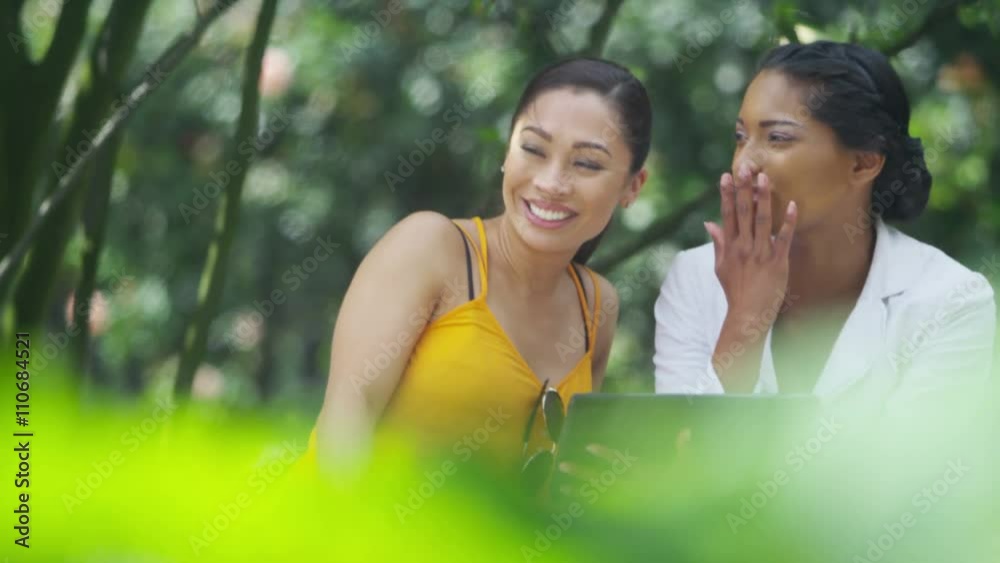 Happy attractive female friends using tablet computer outdoors in summer Happy attractive female friends using tablet computer outdoors in summer