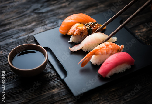 close up of sashimi sushi set with chopsticks and soy on black background