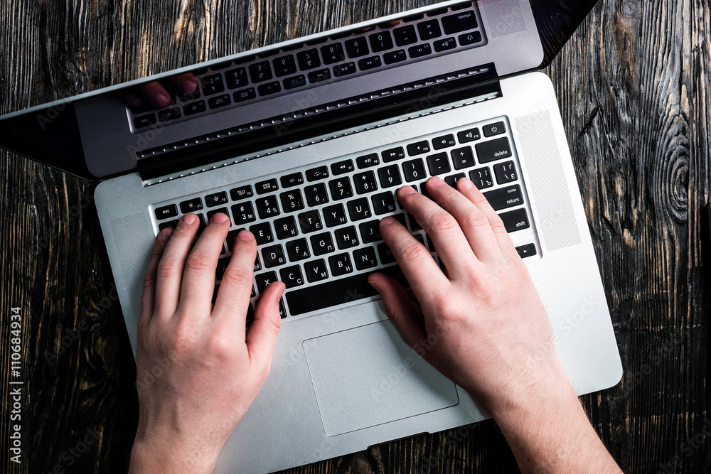 Fototapeta premium hands typing on grey notebook on dark wooden table top view