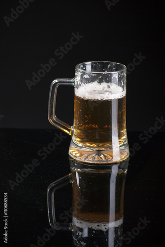 Beer glass with background and shinny reflection on bottom with beer falling into glass