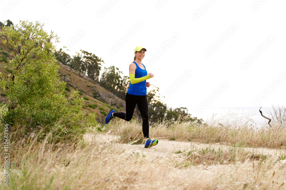 Sporty woman running on trail outdoors in baseball cap Sporty woman running on trail outdoors in baseball cap
