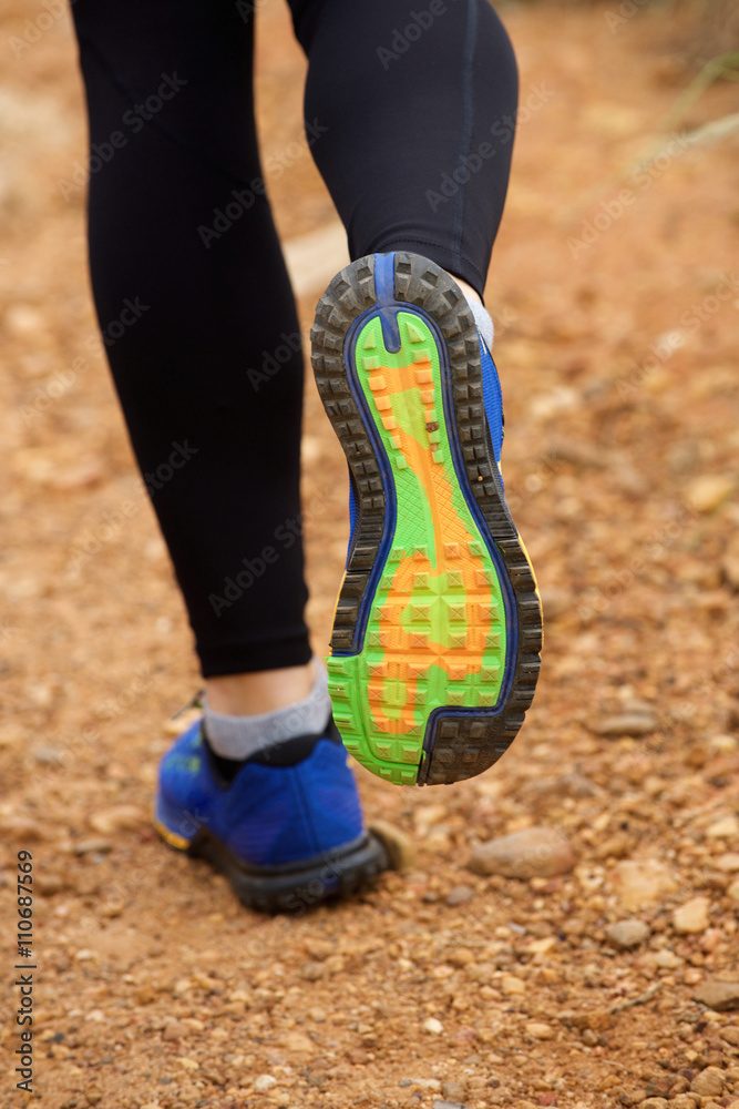 Close up of woman's sneakers running on dirt road