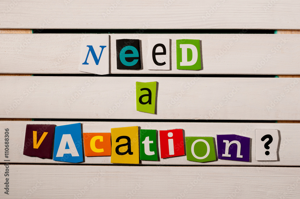 Need a vacation - written with color magazine letter clippings on wooden board Need a vacation - written with color magazine letter clippings on wooden board
