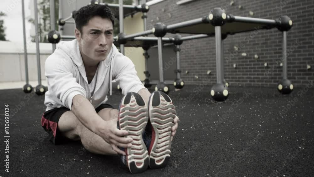 Very fit Asian man stretching out in outdoor urban environment. Very fit Asian man stretching out in outdoor urban environment.