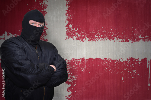 Canvas Print dangerous man in a mask standing near a wall with painted national flag of denma