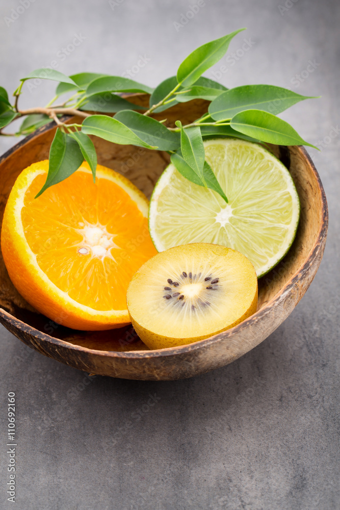 Mixed citrus fruit lemons, orange, kiwi, limes on a gray backgro Mixed citrus fruit lemons, orange, kiwi, limes on a gray backgro