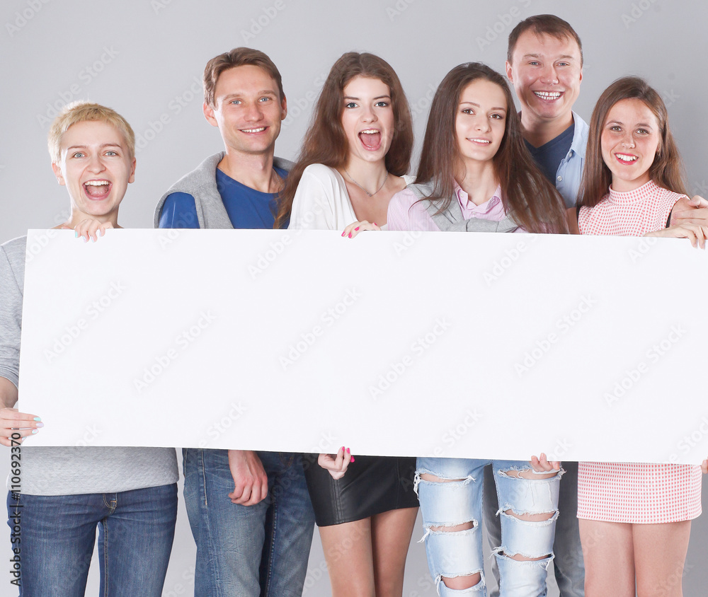 Happy young group of people standing together and holding a blank Happy young group of people standing together and holding a blank