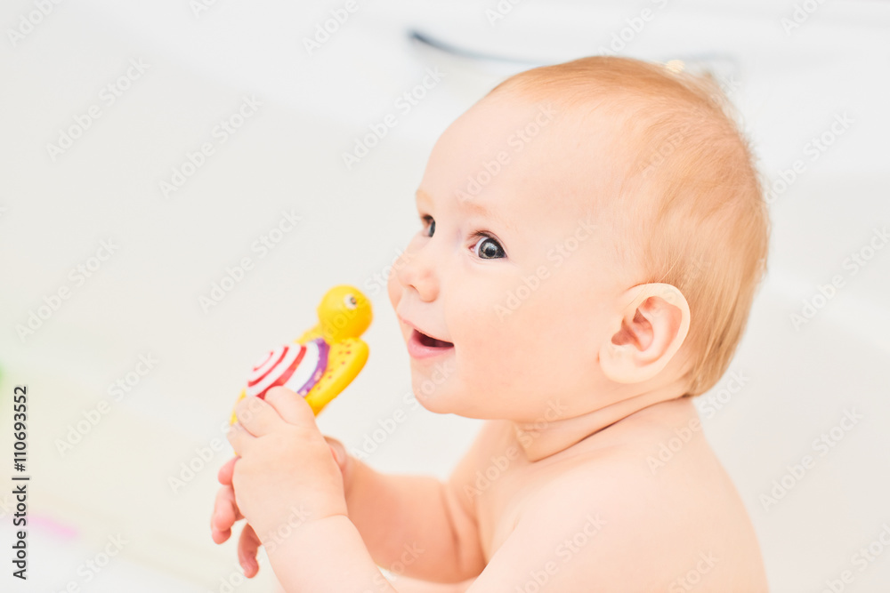 Portrait one year old baby in a white tub with a toy in the hands Portrait one year old baby in a white tub with a toy in the hands