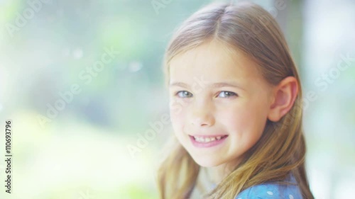  Portrait of pretty smiling little girl sitting by a window.