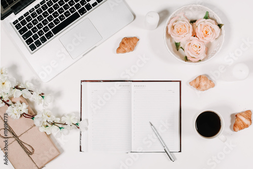 Workspace with diary, pen, vintage white tray, sakura, roses, croissants and coffee on white background. Top view, flat lay
