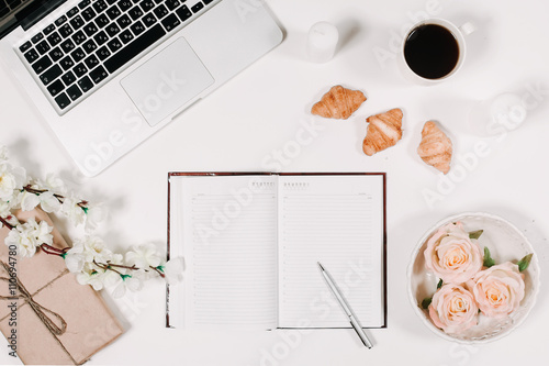Workspace with diary, pen, vintage white tray, sakura, roses, croissants and coffee on white background. Top view, flat lay