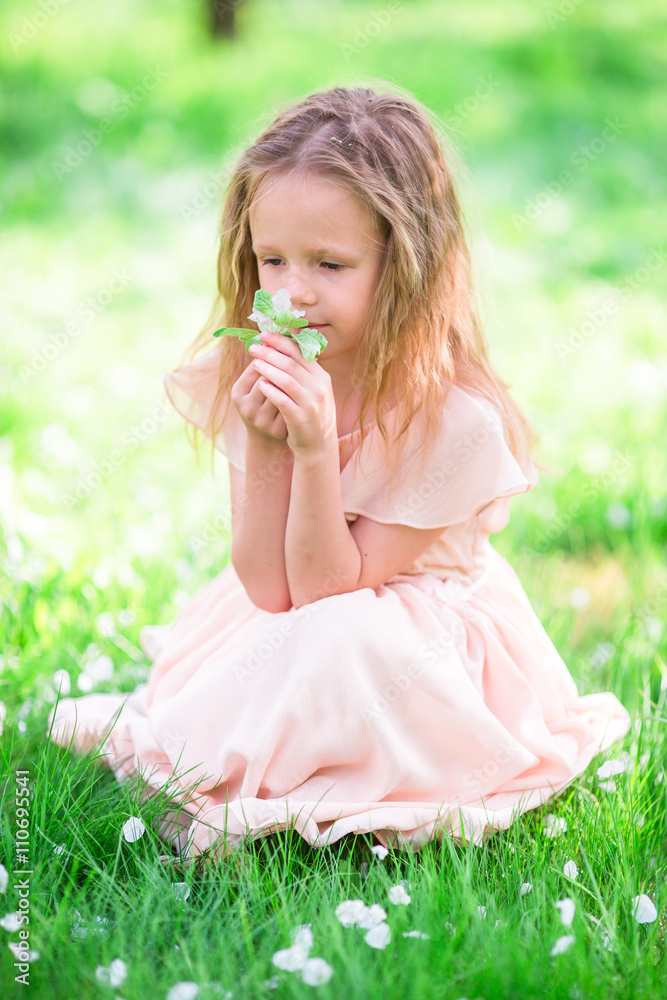 Adorable little girl enjoying smell in a flowering spring garden Adorable little girl enjoying smell in a flowering spring garden