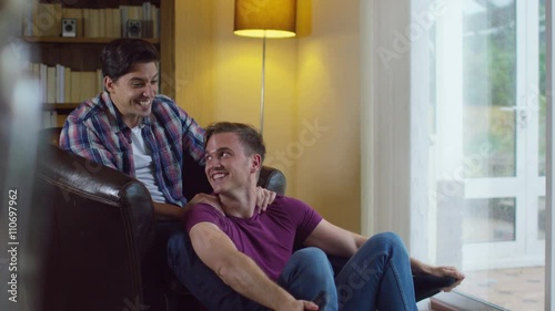 Attractive young gay couple relaxing at home and chatting photo