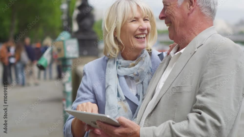 Portrait of happy mature couple looking at computer tablet in the city Portrait of happy mature couple looking at computer tablet in the city