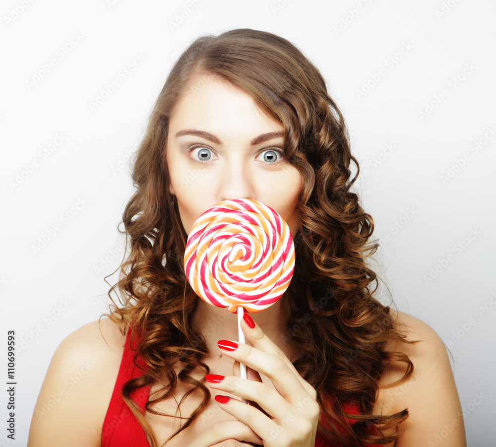 portrait of a smiling cute girl covering her lips with lollipop