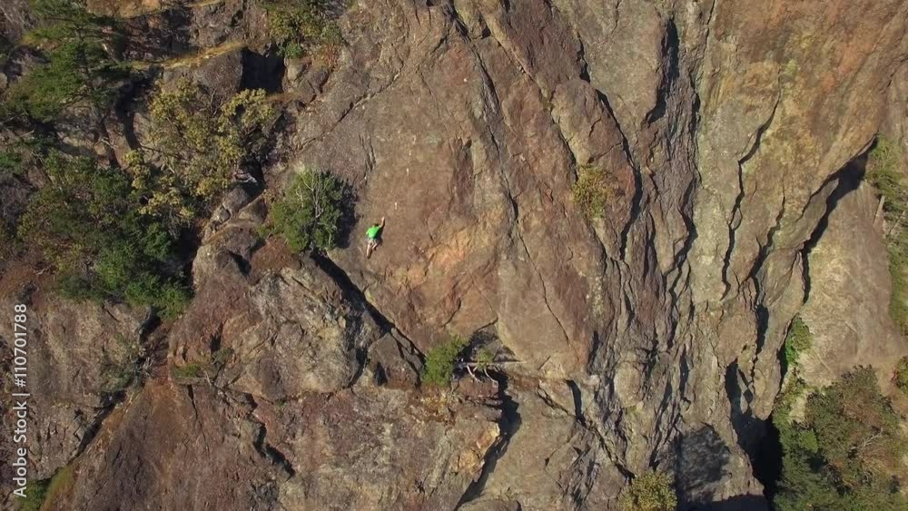 Aerial of Rock Climber Maneuvering Up Mountain Cliff on Sunny Day Aerial of Rock Climber Maneuvering Up Mountain Cliff on Sunny Day