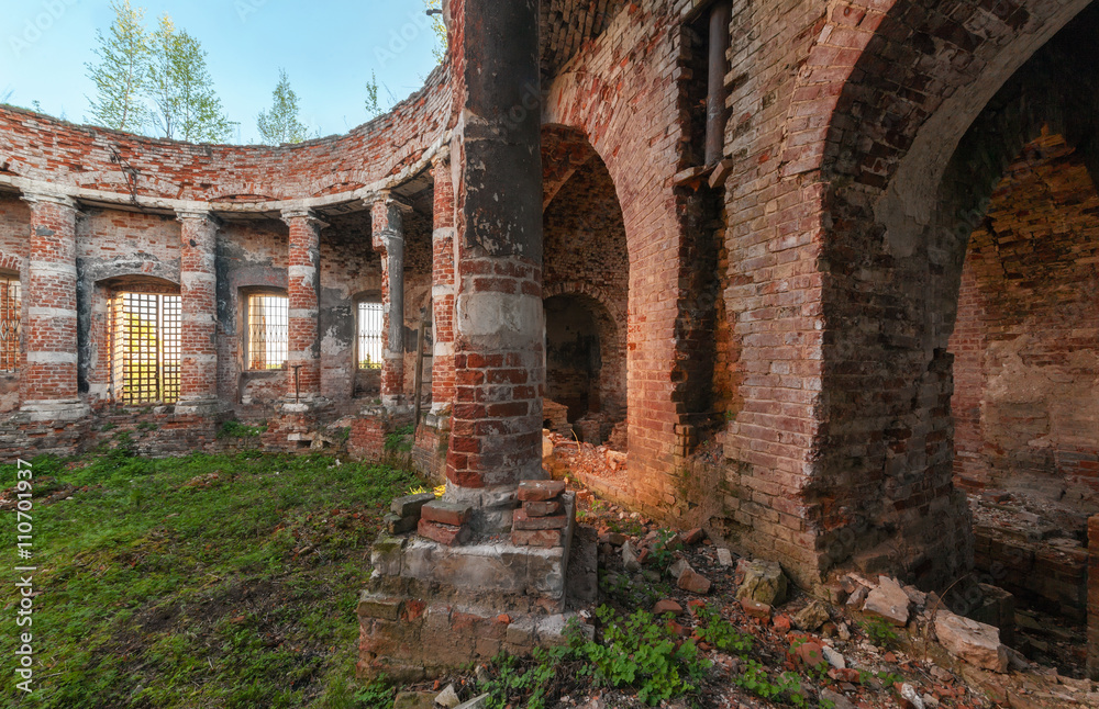 Ancient rotunda with columns without a dome. The brick ruins of the interior of an abandoned temple overgrown with grass