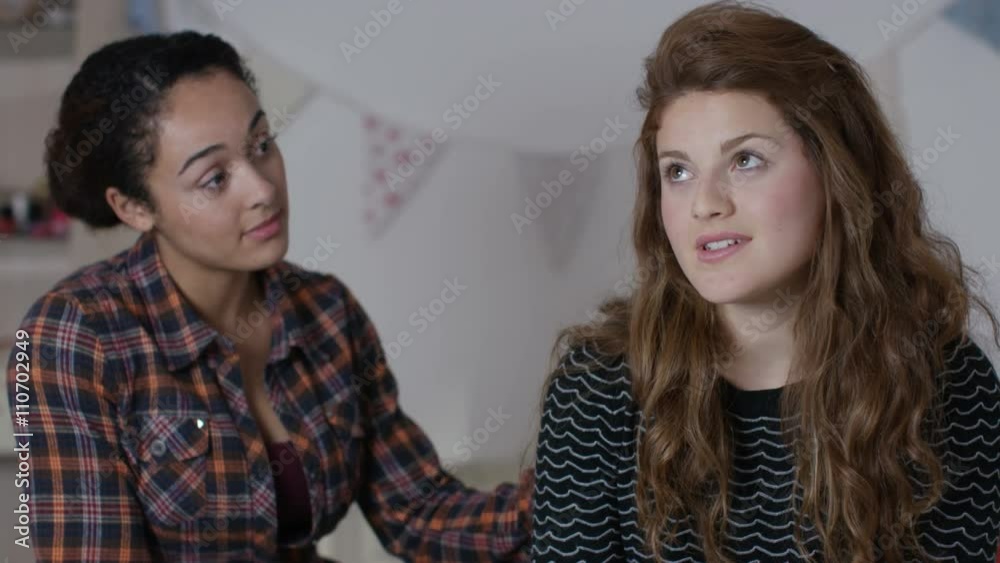 Teenage girls in bedroom, one girl tries to comfort her sad friend Teenage girls in bedroom, one girl tries to comfort her sad friend