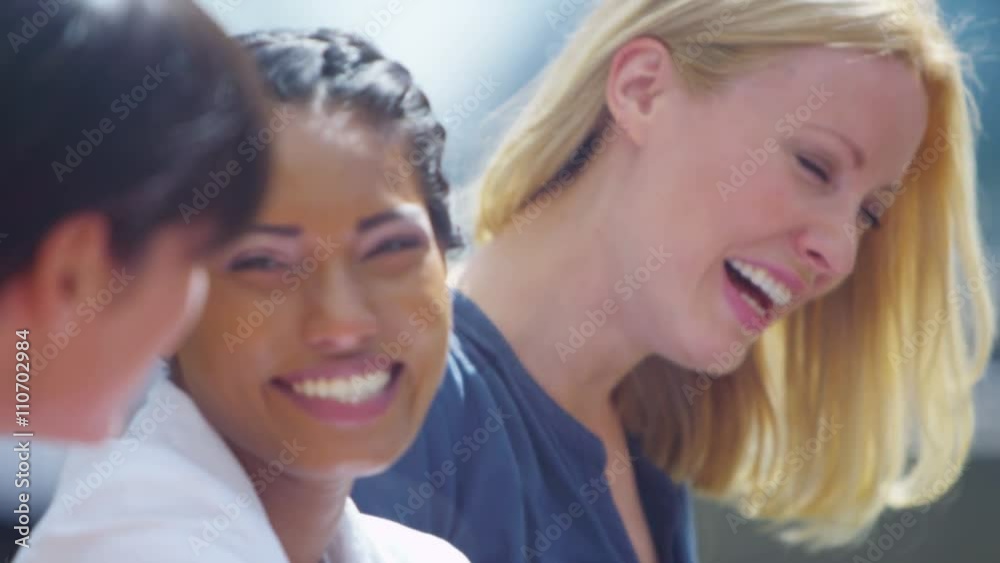 Portrait attractive female friends chatting & laughing outdoors in city Portrait attractive female friends chatting & laughing outdoors in city