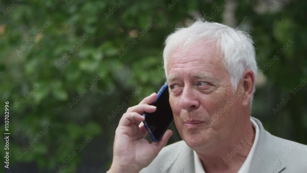 Portrait of happy mature man talking on mobile phone in urban park area Portrait of happy mature man talking on mobile phone in urban park area