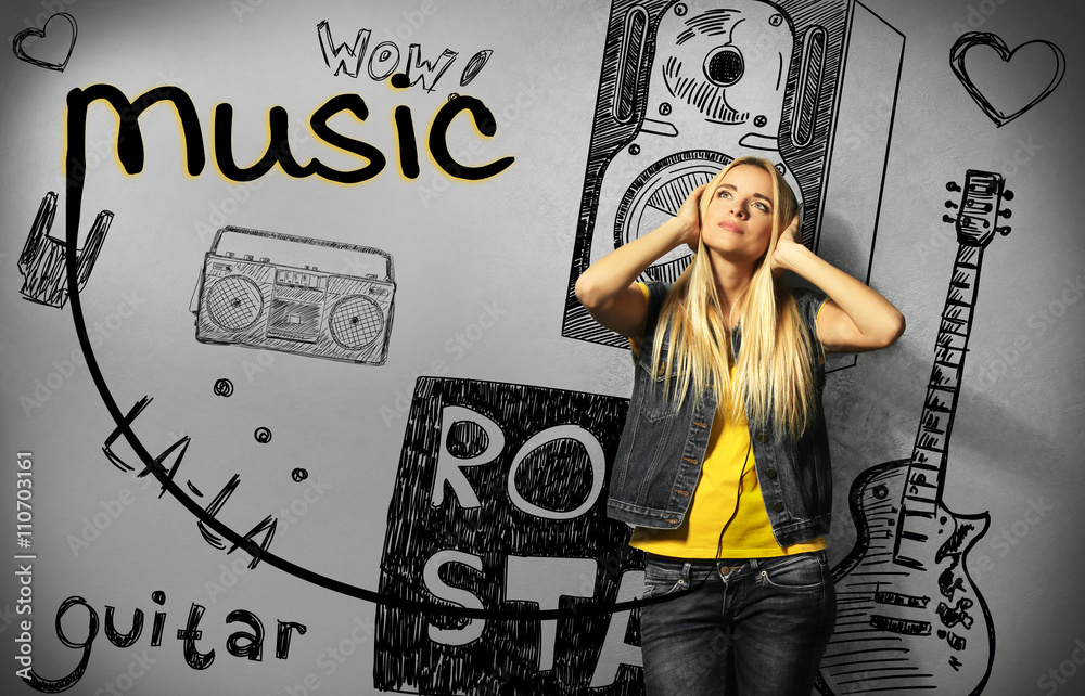 Fototapeta premium Young woman listening to music on grey wall background