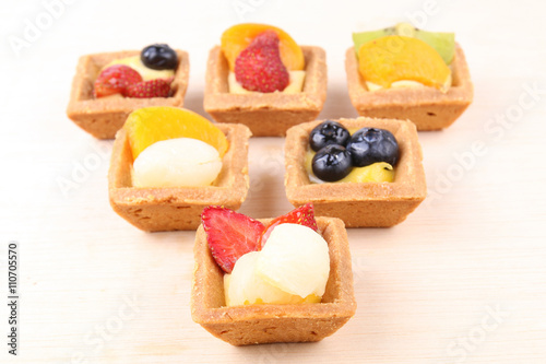 Assorted fruit tarts on wooden surface