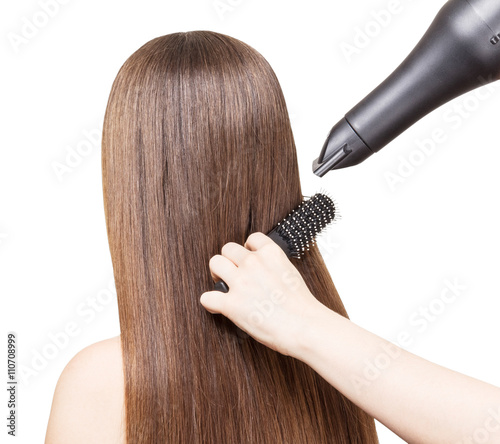 Drying long brown hair with hairdryer and comb isolated.