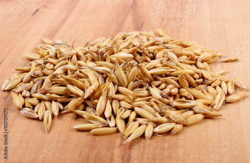 Heap of organic oat grains on wooden table, healthy nutrition