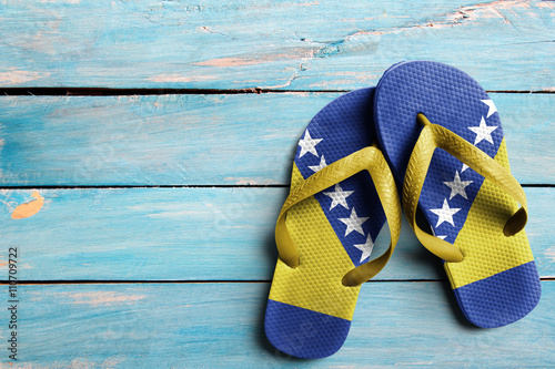 Thongs with flag of Bosnia and Hertzegovina, on blue wooden boards photo