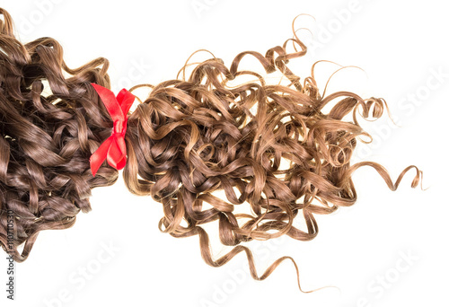 Brown wavy hair tied red ribbon isolated on white.