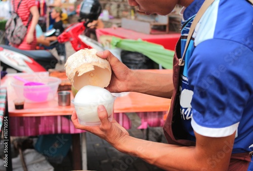  The man Peeling a coconut on a street
