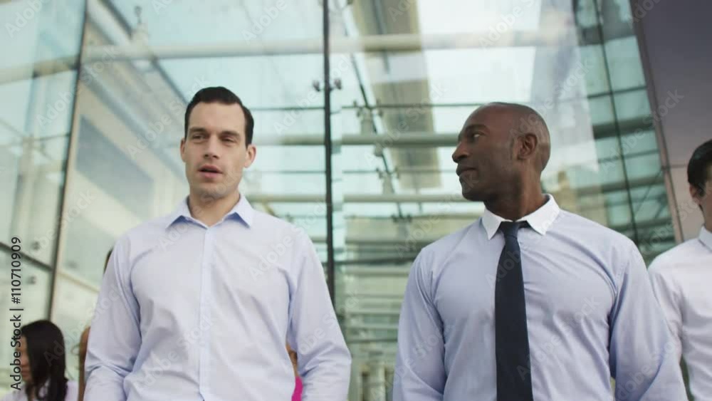  Mixed ethnicity business team walking together outside office building