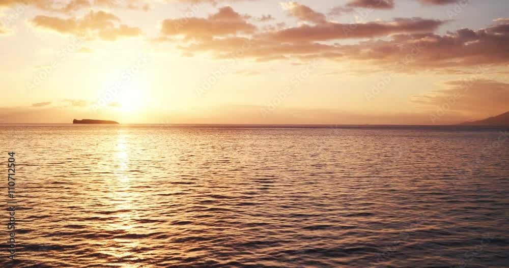 Aerial view flying over ocean into sunset, flying over water into beautiful sunset