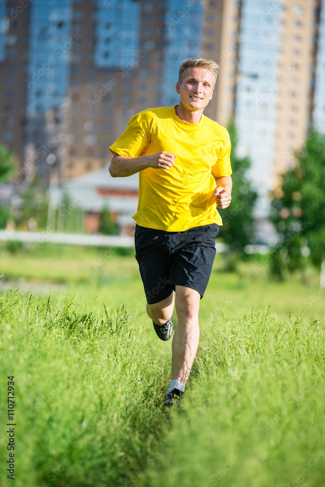 Running man jogging in city street park at beautiful summer day. Sport fitness model caucasian ethnicity training outdoor. Running man jogging in city street park at beautiful summer day. Sport fitness model caucasian ethnicity training outdoor.