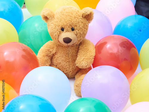 Teddy bear in colourful balloons closeup.