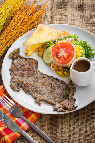 Beef steak with black pepper sauce , salad and French fries on s photo