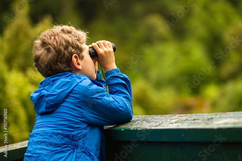 young boy bird watching in a forest