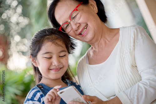 Photography Little Asian girl using mobile phone with her grandmother